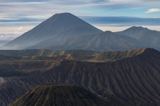 Mount Bromo volcano at sunrise, viewed from King Kong viewpoint in Bromo Tengger Semeru National Park, East Java, Indonesia. Active crater smoke, Mount Semeru cone, clouds, and vast ash plain.