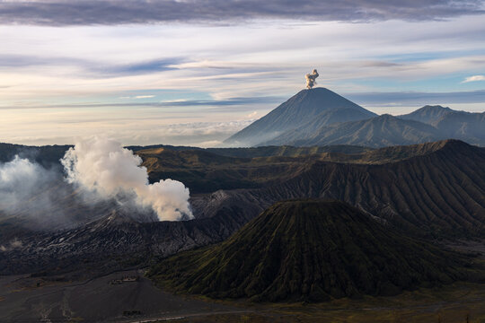 Mount Bromo volcano at sunrise, viewed from King Kong viewpoint in Bromo Tengger Semeru National Park, East Java, Indonesia. Active crater smoke, Mount Semeru cone, clouds, and vast ash plain.