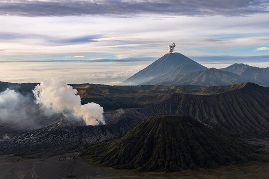 Mount Bromo volcano at sunrise, viewed from King Kong viewpoint in Bromo Tengger Semeru National Park, East Java, Indonesia. Active crater smoke, Mount Semeru cone, clouds, and vast ash plain.