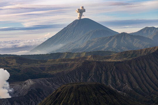 Mount Bromo volcano at sunrise, viewed from King Kong viewpoint in Bromo Tengger Semeru National Park, East Java, Indonesia. Active crater smoke, Mount Semeru cone, clouds, and vast ash plain.