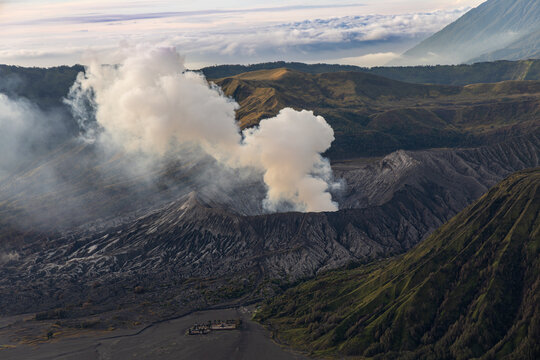Mount Bromo volcano at sunrise, viewed from King Kong viewpoint in Bromo Tengger Semeru National Park, East Java, Indonesia. Active crater smoke, Mount Semeru cone, clouds, and vast ash plain.