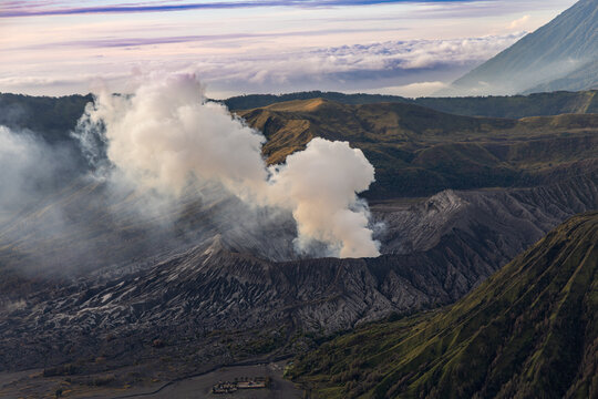 Mount Bromo volcano at sunrise, viewed from King Kong viewpoint in Bromo Tengger Semeru National Park, East Java, Indonesia. Active crater smoke, Mount Semeru cone, clouds, and vast ash plain.