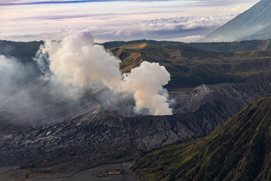 Mount Bromo volcano at sunrise, viewed from King Kong viewpoint in Bromo Tengger Semeru National Park, East Java, Indonesia. Active crater smoke, Mount Semeru cone, clouds, and vast ash plain.