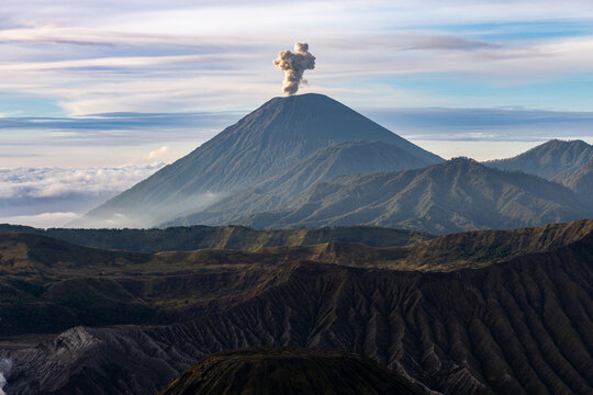 Mount Bromo volcano at sunrise, viewed from King Kong viewpoint in Bromo Tengger Semeru National Park, East Java, Indonesia. Active crater smoke, Mount Semeru cone, clouds, and vast ash plain.