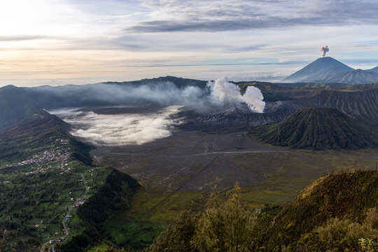 Mount Bromo volcano at sunrise, viewed from King Kong viewpoint in Bromo Tengger Semeru National Park, East Java, Indonesia. Active crater smoke, Mount Semeru cone, clouds, and vast ash plain.