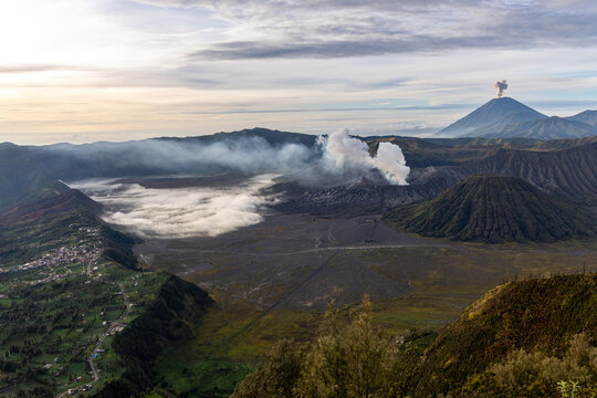 Mount Bromo volcano at sunrise, viewed from King Kong viewpoint in Bromo Tengger Semeru National Park, East Java, Indonesia. Active crater smoke, Mount Semeru cone, clouds, and vast ash plain.