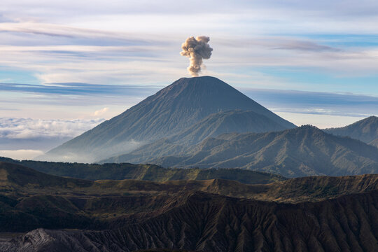 Mount Bromo volcano at sunrise, viewed from King Kong viewpoint in Bromo Tengger Semeru National Park, East Java, Indonesia. Active crater smoke, Mount Semeru cone, clouds, and vast ash plain.