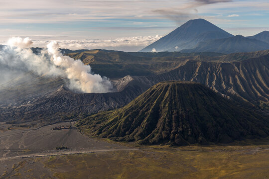 Mount Bromo volcano at sunrise, viewed from King Kong viewpoint in Bromo Tengger Semeru National Park, East Java, Indonesia. Active crater smoke, Mount Semeru cone, clouds, and vast ash plain.