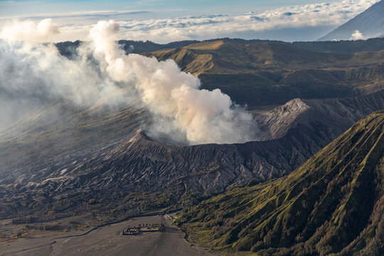 Mount Bromo volcano at sunrise, viewed from King Kong viewpoint in Bromo Tengger Semeru National Park, East Java, Indonesia. Active crater smoke, Mount Semeru cone, clouds, and vast ash plain.