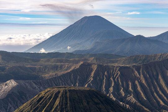 Mount Bromo volcano at sunrise, viewed from King Kong viewpoint in Bromo Tengger Semeru National Park, East Java, Indonesia. Active crater smoke, Mount Semeru cone, clouds, and vast ash plain.
