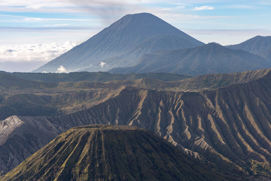 Mount Bromo volcano at sunrise, viewed from King Kong viewpoint in Bromo Tengger Semeru National Park, East Java, Indonesia. Active crater smoke, Mount Semeru cone, clouds, and vast ash plain.