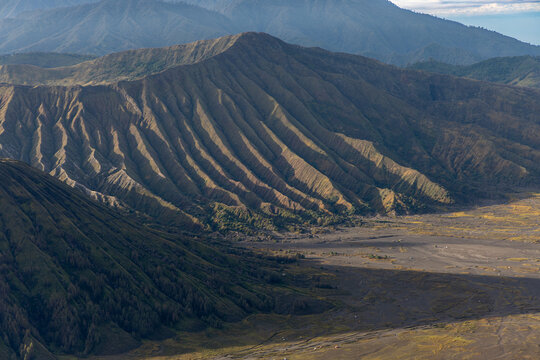 Mount Bromo volcano at sunrise, viewed from King Kong viewpoint in Bromo Tengger Semeru National Park, East Java, Indonesia. Active crater smoke, Mount Semeru cone, clouds, and vast ash plain.