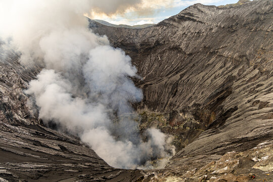 Active Mount Bromo volcano crater with sulfur smoke and volcanic sand sea, Tengger Semeru National Park, East Java, Indonesia.