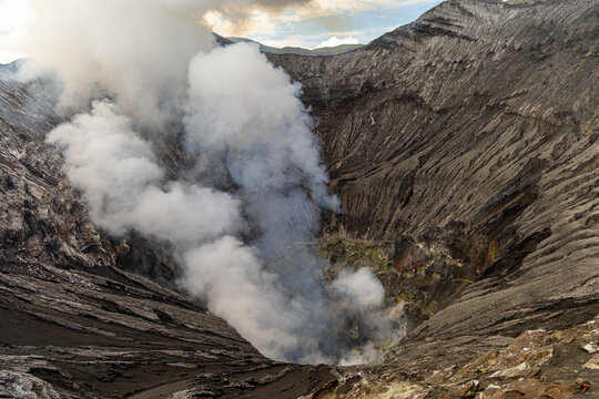 Active Mount Bromo volcano crater with sulfur smoke and volcanic sand sea, Tengger Semeru National Park, East Java, Indonesia.