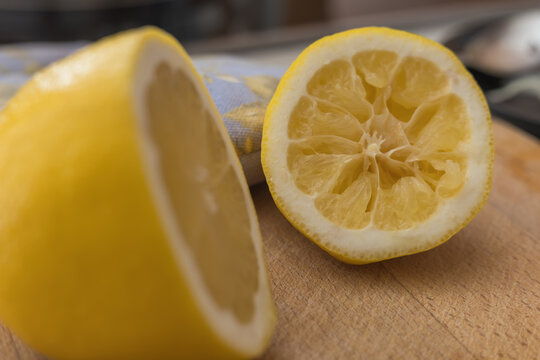 Fresh juicy yellow lemon cut in half sitting on wooden kitchen cutting board