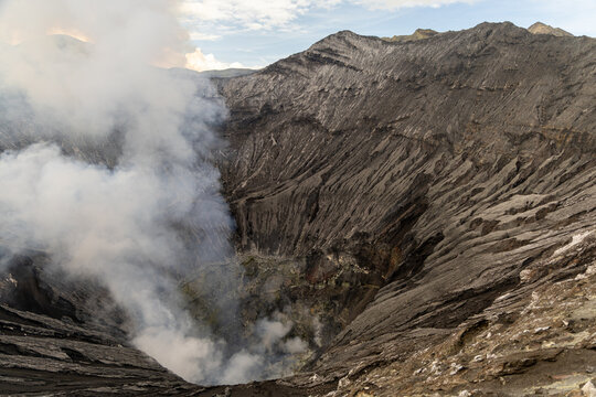 Active Mount Bromo volcano crater with sulfur smoke and volcanic sand sea, Tengger Semeru National Park, East Java, Indonesia.