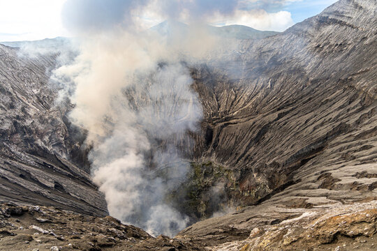 Active Mount Bromo volcano crater with sulfur smoke and volcanic sand sea, Tengger Semeru National Park, East Java, Indonesia.