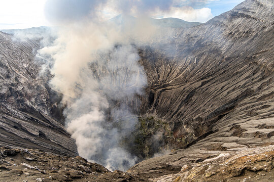 Active Mount Bromo volcano crater with sulfur smoke and volcanic sand sea, Tengger Semeru National Park, East Java, Indonesia.