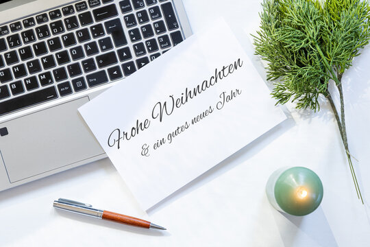 Weihnachtsgr&uuml;&szlig;e und Silvestergr&uuml;&szlig;e f&uuml;r Gesch&auml;ftskunden mit Laptop, Gru&szlig;karte und dezenter Weihnachtsdekoration auf einem hellen Schreibtisch