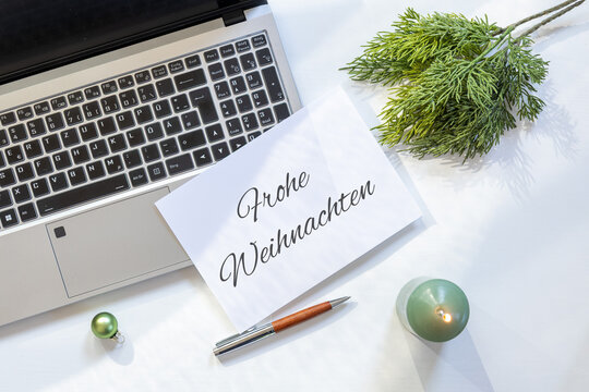 Weihnachtsgr&uuml;&szlig;e f&uuml;r Gesch&auml;ftskunden mit Laptop, Gru&szlig;karte und dezenter Weihnachtsdekoration auf einem hellen Schreibtisch