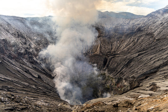Active Mount Bromo volcano crater with sulfur smoke and volcanic sand sea, Tengger Semeru National Park, East Java, Indonesia.