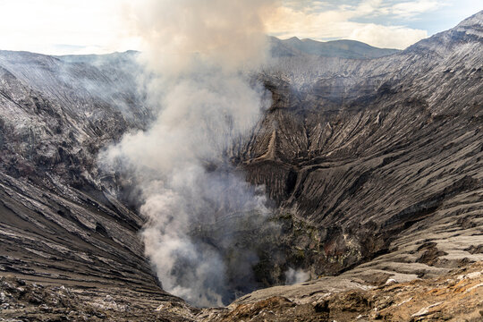 Active Mount Bromo volcano crater with sulfur smoke and volcanic sand sea, Tengger Semeru National Park, East Java, Indonesia.