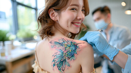 Fototapeta premium woman receiving a colorful hummingbird tattoo on her shoulder blade, close-up focus on the tattooed skin, bright airy tattoo studio, artist applying vibrant blue and green ink, detailed needlework, 
