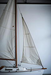 Fototapeta premium Nautical adventure and travel exploration, vintage model sailboat with white sails and wooden mast isolated on a clean neutral studio background