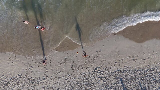 Top-down aerial view of two people playing altinho, keeping a soccer ball in the air, on Copacabana Beach in Rio de Janeiro, Brazil. 