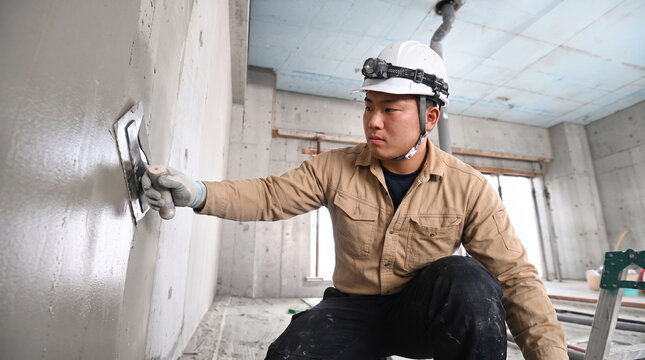コテで壁面を仕上げる左官職人の建設現場