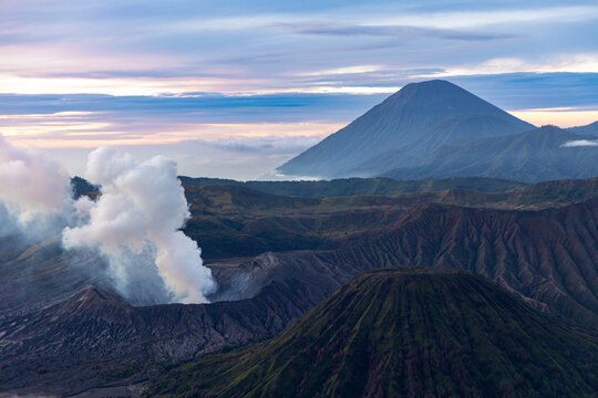Mount Bromo volcano at sunrise, viewed from King Kong viewpoint in Bromo Tengger Semeru National Park, East Java, Indonesia. Active crater smoke, Mount Semeru cone, clouds, and vast ash plain.