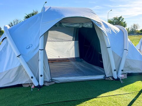 Camping tent pitched on green grass at outdoor retail exhibition.