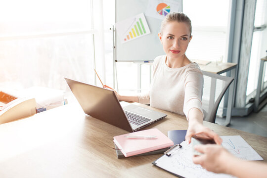 A picture of business woman getting her phone from her helper. She is preparing for skype meeting.