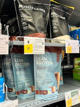Variety of dietary supplements and protein powders on shelves in a modern health food shop. 