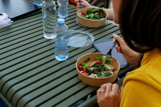 People Eat Salad at a Table With Water Bottles