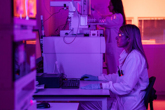 Scientists Work in a Lab With Purple Lighting at Night