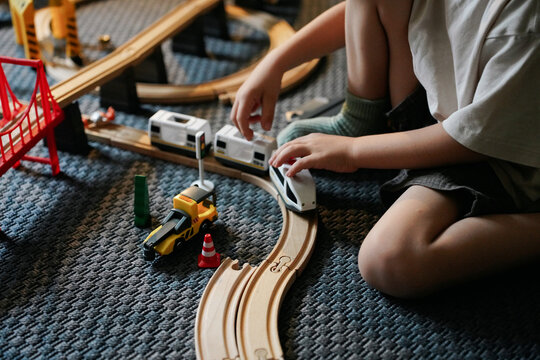 Close-Up of Hands Placing a Toy Train on the Track