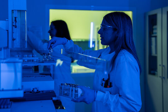 Scientist Works With Lab Equipment in Blue-Lit Laboratory