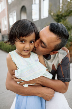 Father kissing daughter in a candid moment of family love