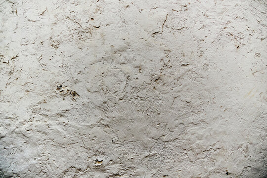 Rough white stucco wall texture with uneven plaster and granular surface