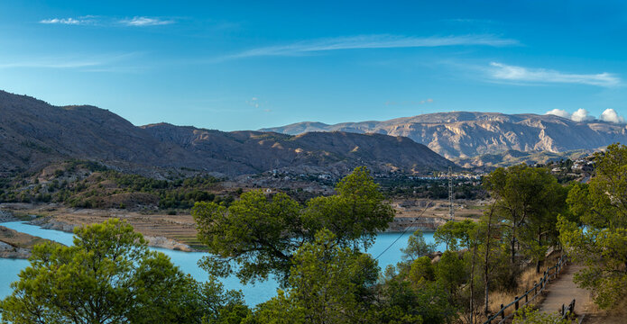 Scenic panoramic view of Amadorio reservoir in Spain with turquoise water and mountains under clear sky