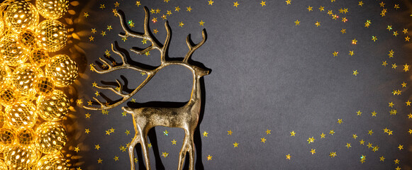Golden Christmas reindeer beside glowing ball lights and scattered stars on dark background for New Year banner or festive greeting design © Svetlana Kolpakova