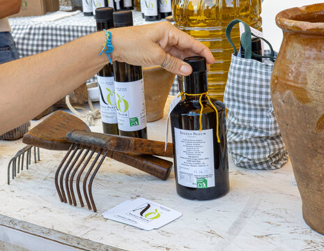 Denia, Spain - September 26, 2026.Hand selecting a bottle of artisanal extra virgin olive oil at a farm market with hand rakes and ceramic jars