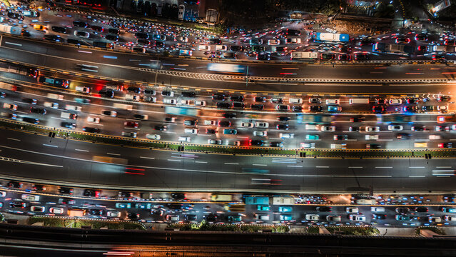 Aerial view of heavy traffic with long exposure light trails on a multi-lane highway at night in Jakarta, Indonesia.