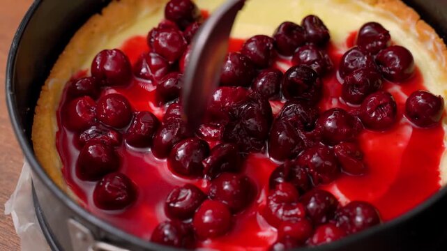 Spreading cherries over cream filling in a baking form, making pie