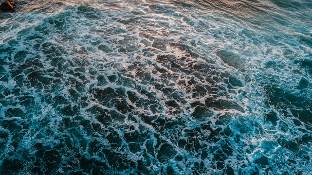 Aerial view of ocean waves with white sea foam and deep blue water in Aimere, East Nusa Tenggara, Indonesia.