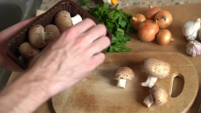 POV hands taking fresh brown champignon mushrooms from wooden bowl to cook healthy low-calorie dish. Vegetarian cuisine, organic seasonal products, autumn harvest ingredients on kitchen table.