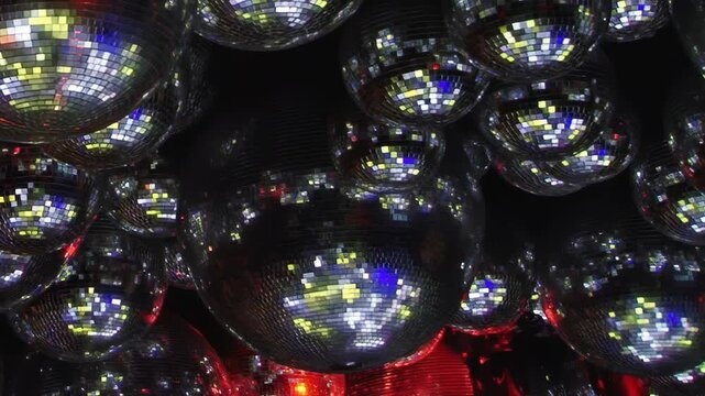 Mirrored Disco Balls Glow With Blue and Red Light. Multiple mirrored spheres fill a dark interior as mosaic tiles catch changing colored light and create shimmering abstract reflections.