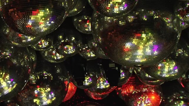 Disco Ball Cluster Glows With Purple and Red Reflections. The mirror ball cluster forms a decorative pattern, with mosaic tiles catching changing colored light across the dark interior.