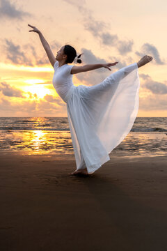 Side view of young gymnast in white clothing posing  standing split at the beach during sunset Sabah Borneo